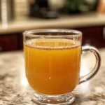 Cup of golden-colored natural Mounjaro drink with visible turmeric and spices